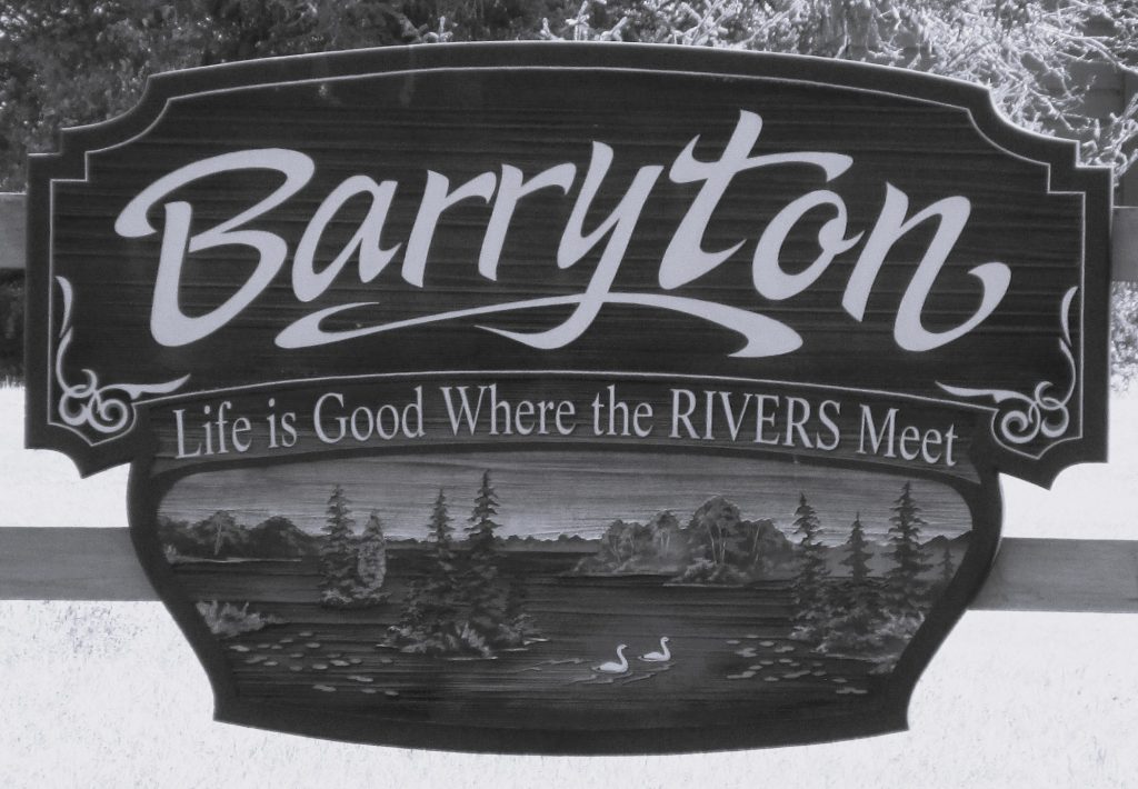 Black and white picture of the Village of Barryton sign. Sign says "Barryton Life is Good Where the RIVERS Meet
